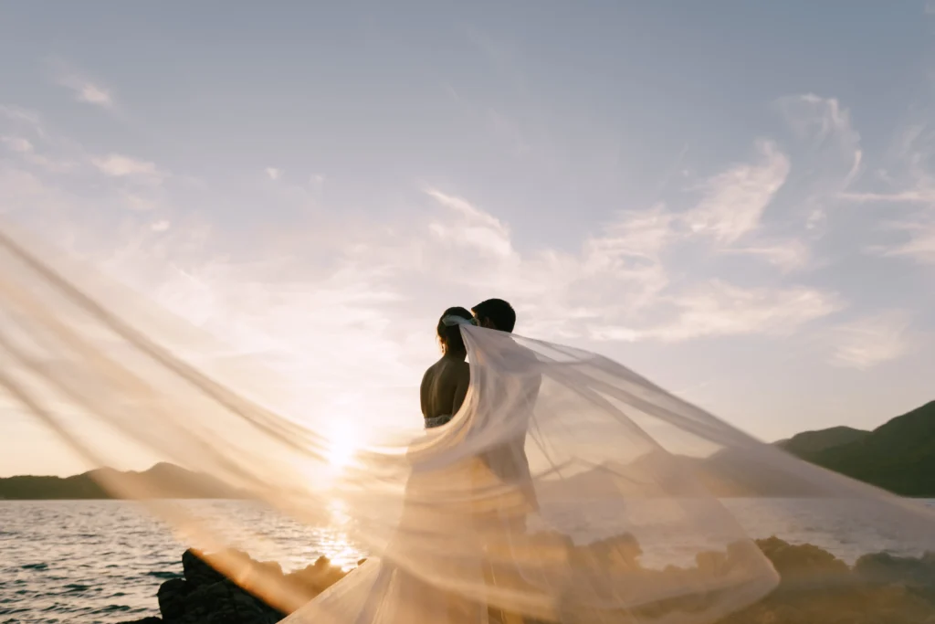 groom-hugs-bride-in-a-veil-fluttering-in-the-wind-2026-03-17-00-03-13-utc.webp