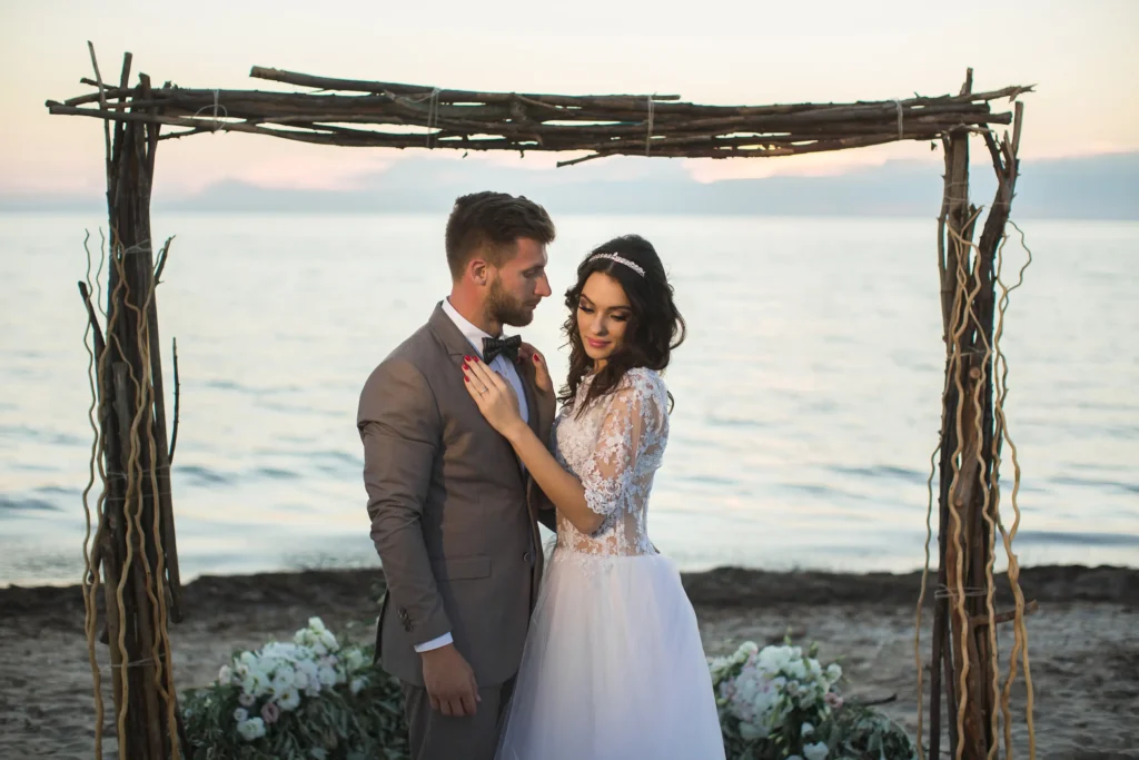 the-bride-and-groom-under-archway-on-beach-sunset-2026-01-07-06-32-41-utc.webp